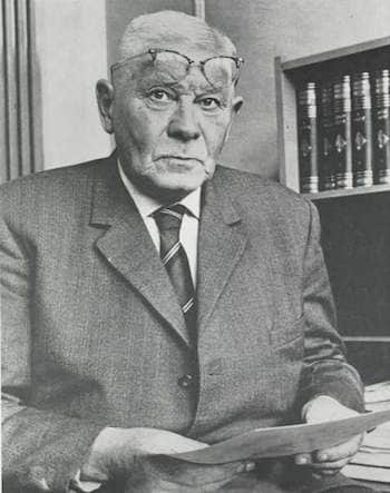 Willem Meiborg, stern look, stiff suit, paper in hand and glasses pushed just above the eyes