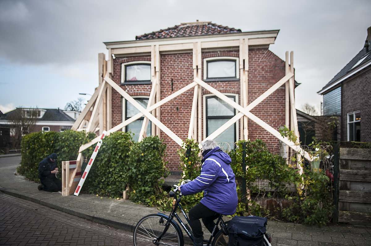 Huis in stutten en een fietser die voorbij fietst voor in beeld